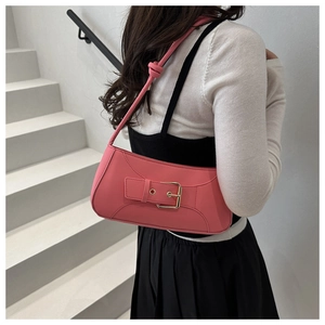 Pink glossy leather shoulder bag with gold buckle worn by model against a minimal staircase