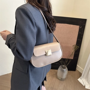 Minimalist beige leather underarm bag with gold buckle on a stylish model in a grey suit