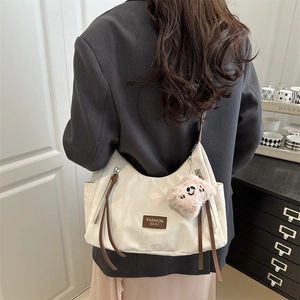 Chic off-white oversized hobo bag with trendy plush charm and leather zipper pulls