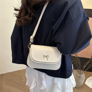 Chic white PU underarm bag with a metal bow accent shown worn by a model in lifestyle shot