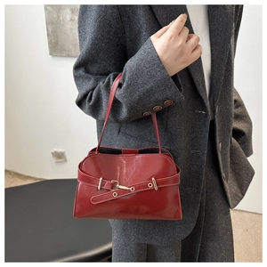Detail der weinroten, glänzenden Muscheltasche mit Vintage-Metallschnalle und Lederriemen