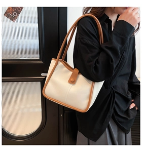 Chic beige tote bag with brown leather contrast handles shown on a shoulder