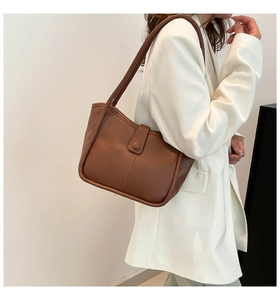 Close-up of brown leather bucket bag with vertical stitching and round snap button