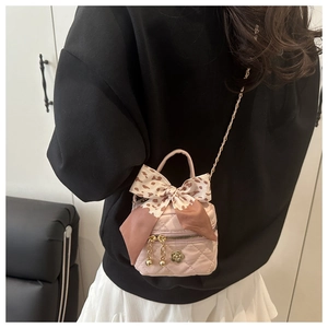 Detail of pink quilted mini handbag with silk scarf bow and gold flower clasp closure