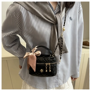 Quilted crossbody bag detail with metallic flower and silk scarf wrapped on handle