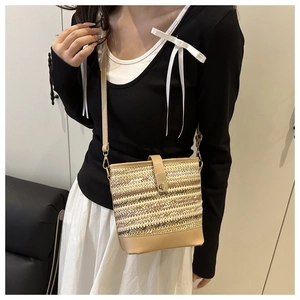 Close-up of woven bucket bag with beige straw texture and brown leather flap detail
