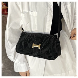 Close-up of black wrinkled patent leather shoulder bag with gold metallic buckle