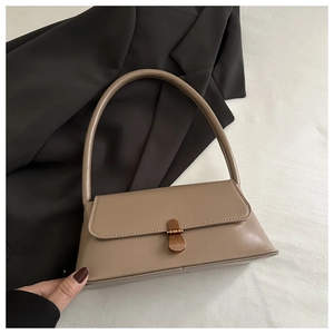 Close-up of khaki baguette bag featuring a vintage gold buckle and smooth leather finish
