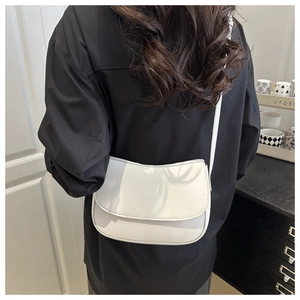 Back view of a model wearing a minimalist white PU leather shoulder bag with a curved base