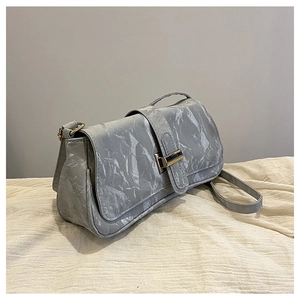Detail view of grey marble textured baguette bag with metallic square buckle on fabric