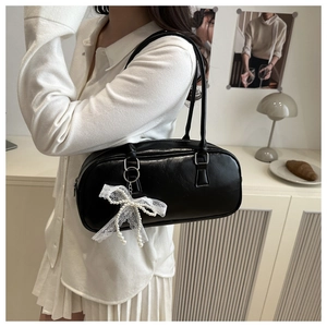 Detail of black Boston bag with white lace pearl bow charm on a leather shoulder strap