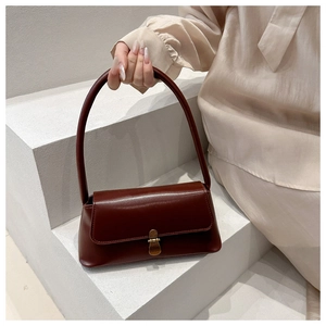 Close-up of deep red vintage leather baguette bag with a golden metallic buckle