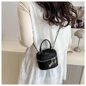 Detail of black quilted crossbody bag with chain strap and flower charm on a model