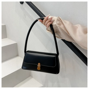 Close-up of minimalist black leather shoulder bag with a polished gold metal clasp detail
