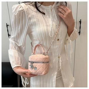Detailed view of pink quilted leather bag with chain strap and flower pendant charm