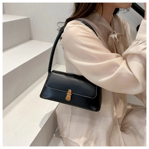 Close-up of black matte faux leather handbag with vintage gold metal buckle on white stairs