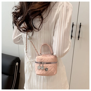Detailed shot of pink quilted crossbody bag with camellia hardware and chain strap