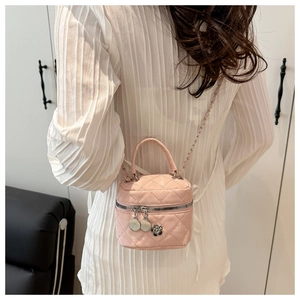 Detailed close-up of pink quilted leather box bag with camellia and cherry charms