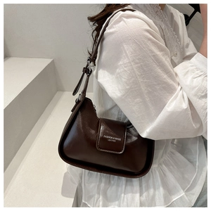 Close-up of dark brown leather underarm bag with white logo and silver buckles