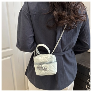 Detail of mint green quilted mini bag with silver chain strap and flower charm zipper