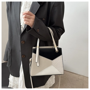 Detailansicht der geometrischen Patchwork-Handtasche mit Kroko-Textur und Gold-Hardware