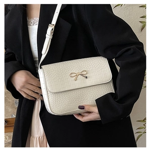 Vue détaillée du sac crème à motif crocodile avec son fermoir doré en forme de nœud chic