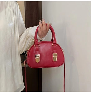 Dettaglio borsa rossa in pelle PU con finiture dorate e maniglie di trasporto