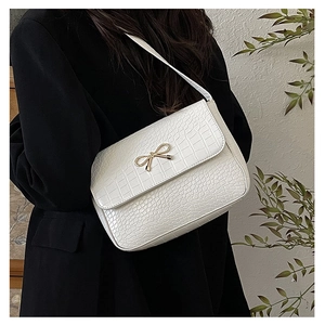 Détail du sac à bandoulière blanc motif crocodile avec fermoir nœud en métal doré
