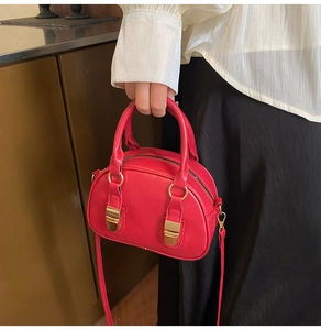 Dettaglio della borsa a conchiglia rossa con fibbie dorate portata dalla modella