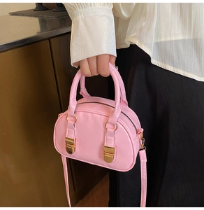 Dettaglio mini borsa a conchiglia rosa lucida con fibbie dorate e doppi manici