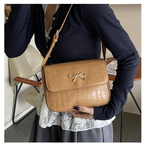 Gros plan du sac bandoulière camel motif crocodile avec fermoir nœud doré chic