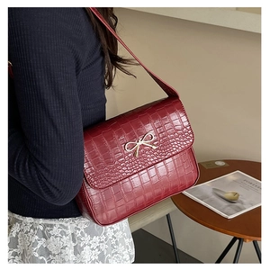 Détail du sac à main bordeaux à motif crocodile avec fermoir nœud papillon en métal doré