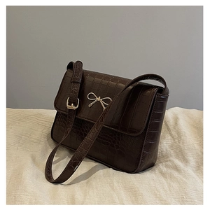 Détail du sac marron foncé effet crocodile avec nœud doré et bandoulière réglable