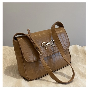Détail du sac en cuir marron texture crocodile avec boucle nœud en métal argenté