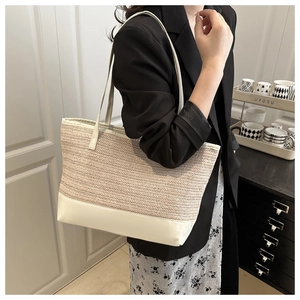 Detail of woven straw shoulder bag with creamy white leather base and shoulder strap