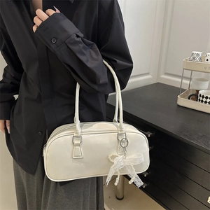 Elegant creamy white Boston handbag with lace bow and pearl charm in a minimalist setting