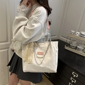 White tote bag with pink leather label, pearl chains and a lace bow for commuting