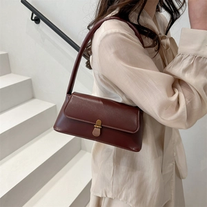 Retro burgundy baguette shoulder bag with gold metal clasp on minimalist white staircase