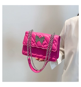 Detail of rose pink quilted crossbody bag featuring silver butterfly and fashion logo