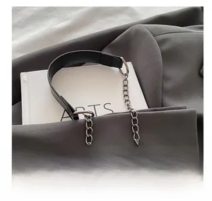 Detail of a chic shoulder bag featuring a mixed black faux leather and gunmetal chain strap