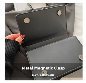 Close-up detail showing the magnetic snap closure on a black textured crossbody bag