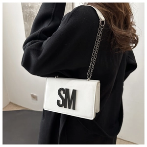 Detail of white rectangle flap bag with black SM letter and silver chain strap