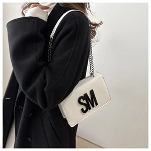 Detail of white leather crossbody bag featuring a black SM 3D logo and chain strap