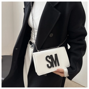 Detailed view of white leather chain bag featuring bold black SM letter decoration