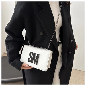 Detail of white leather crossbody bag with 3D black SM logo and metal chain strap