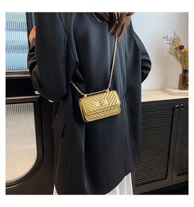 Close-up of golden mini crossbody bag with chevron quilting and metal twist lock