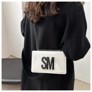 Detail of white square crossbody bag with black SM letter and elegant chain strap