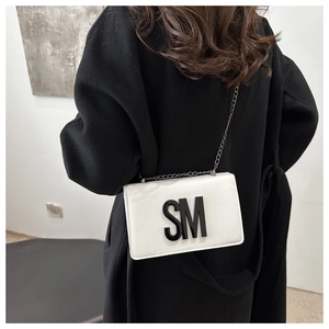 Back view of a model wearing a white crossbody bag with bold black SM letter decor
