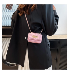 Detail of pink quilted crossbody bag with golden twist lock and chain strap on a model