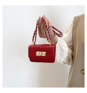 Detail of red quilted mini crossbody bag with gold twist lock and metal chain strap